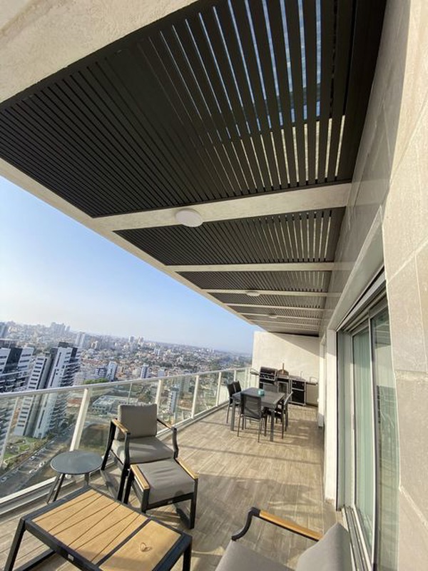 פרגולת אלומיניום שחורה עם למלות במרפסת שמש בקומה גבוהה עם נוף פנורמי לעיר
