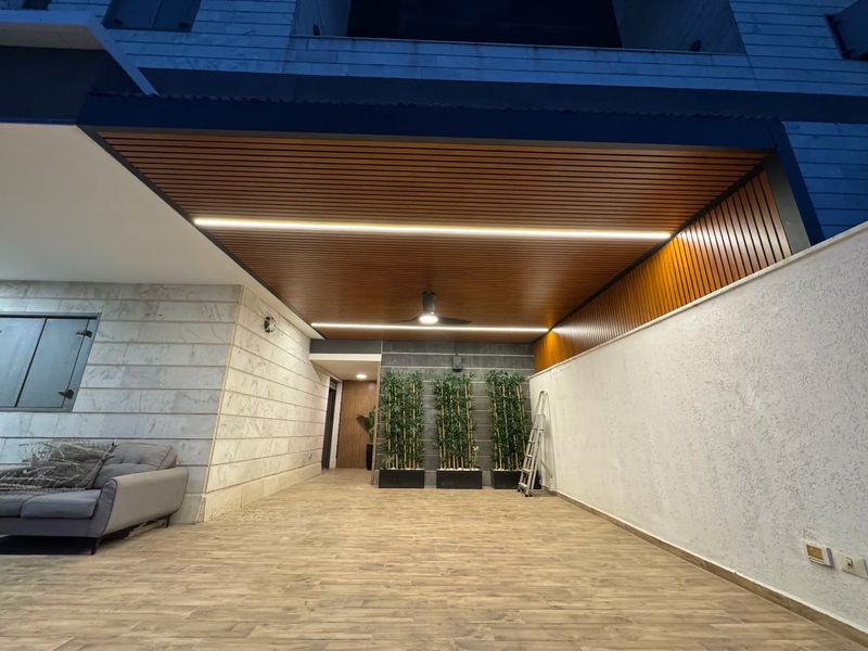 פרגולת אלומיניום דמוי עץ עם תאורת LED משולבת במרפסת שמש בשעות הערב
